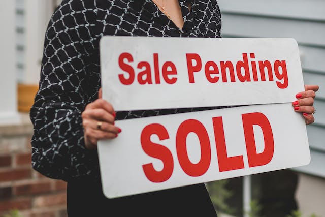 Red real estate sale signs “Sale Pending” and “Sold”